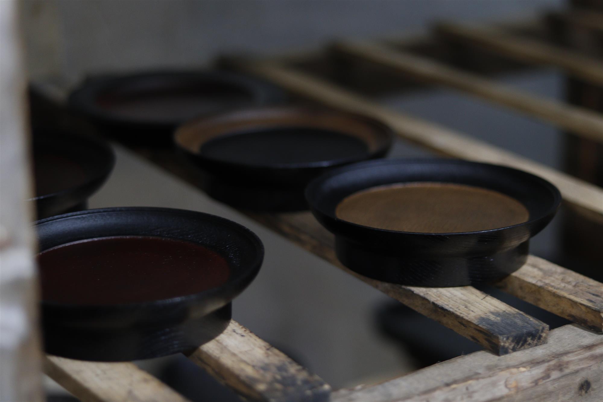 Lacquered wooden bowls resting on workshop shelves