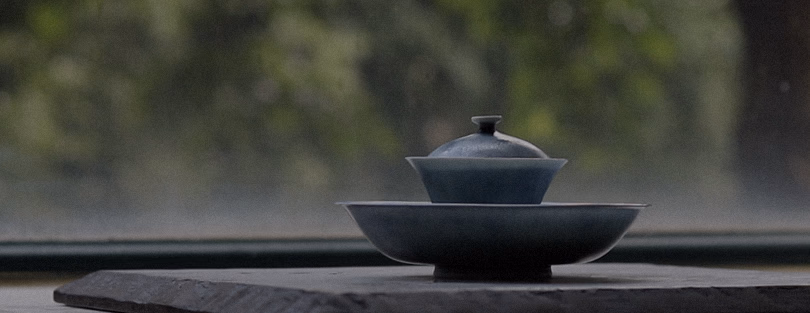 A dark ceramic gaiwan and tea bowl