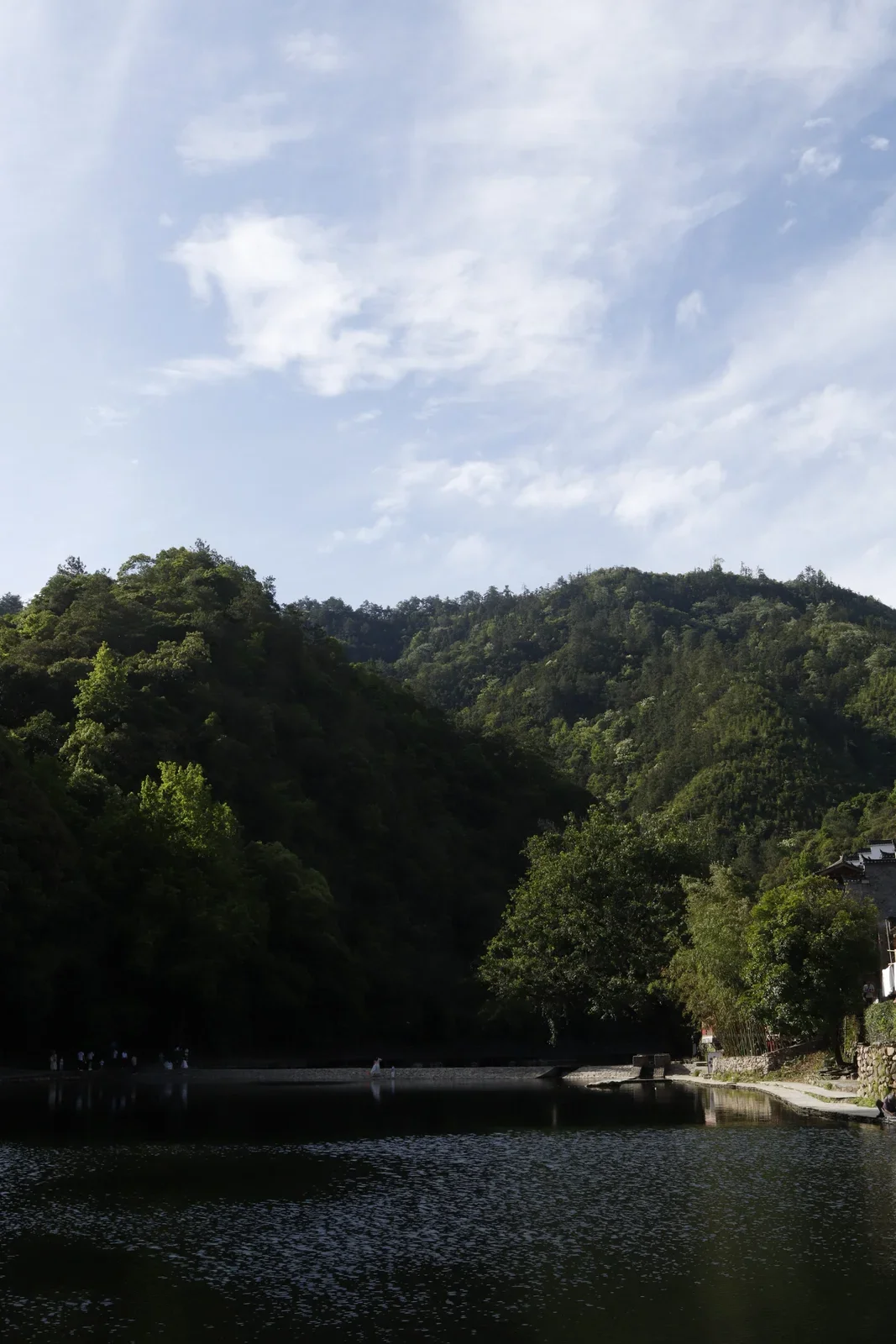A stone crossing over water beneath forested hills in Fuliang