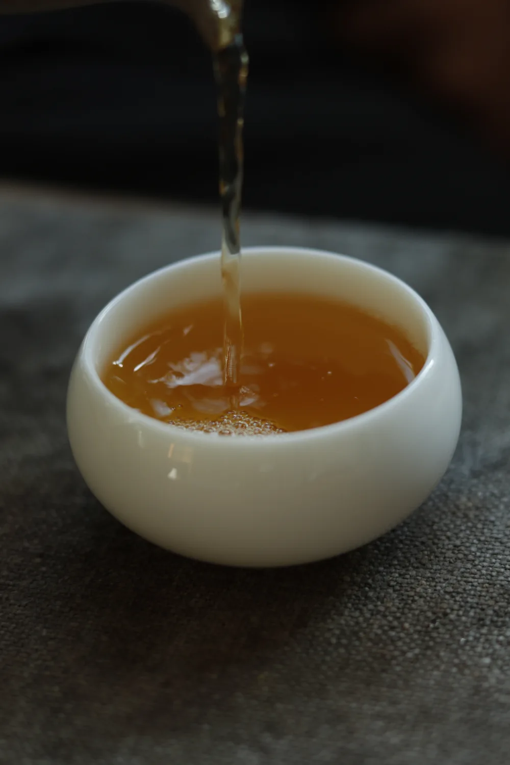 Dianhong Golden Needles tea being poured into a white porcelain cup