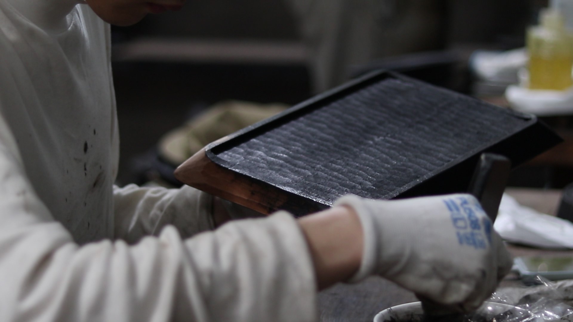A craftsperson working on a textured lacquered wooden tray in the Chiju workshop