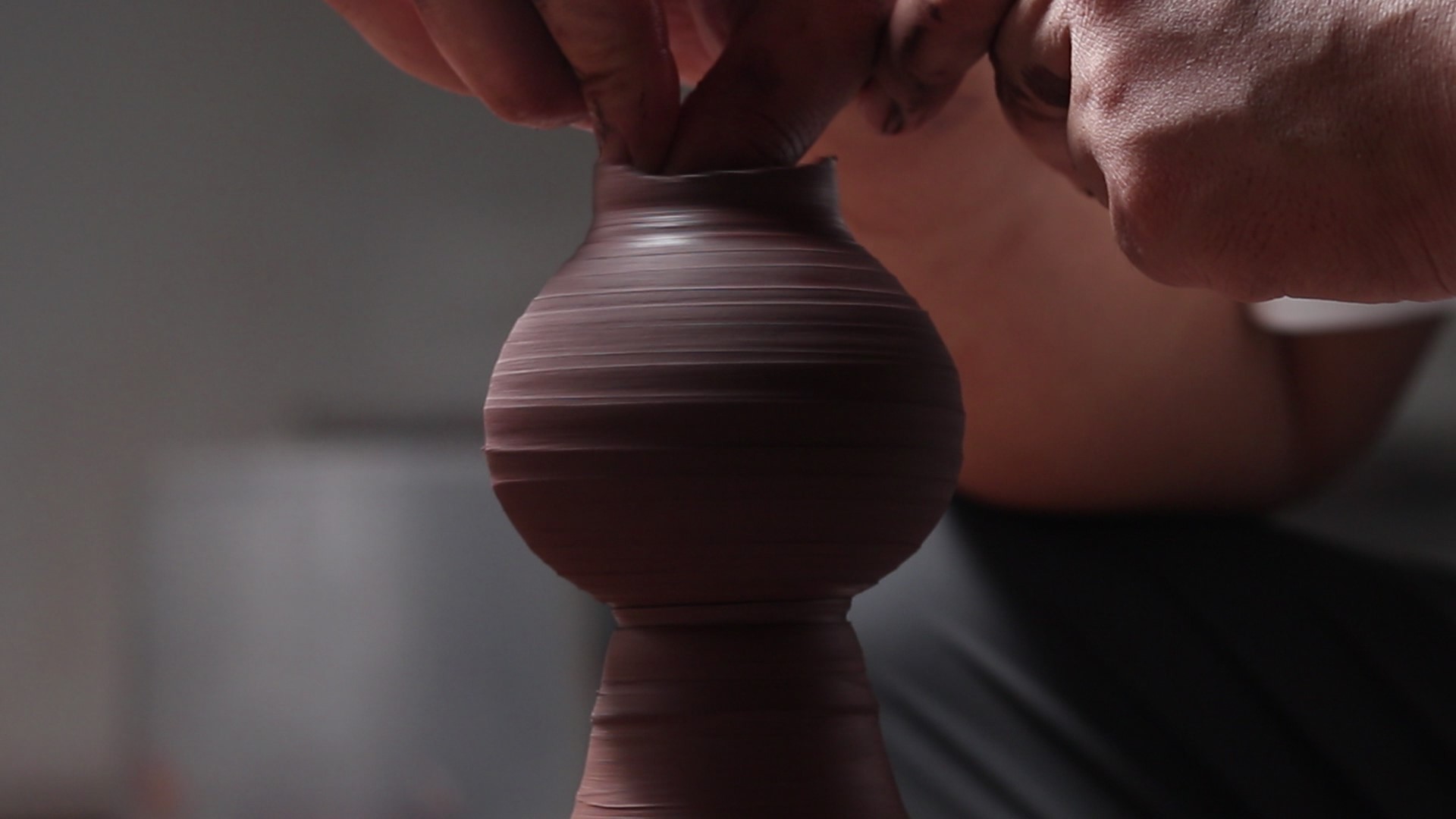 Yizhi shaping a clay vessel on the pottery wheel