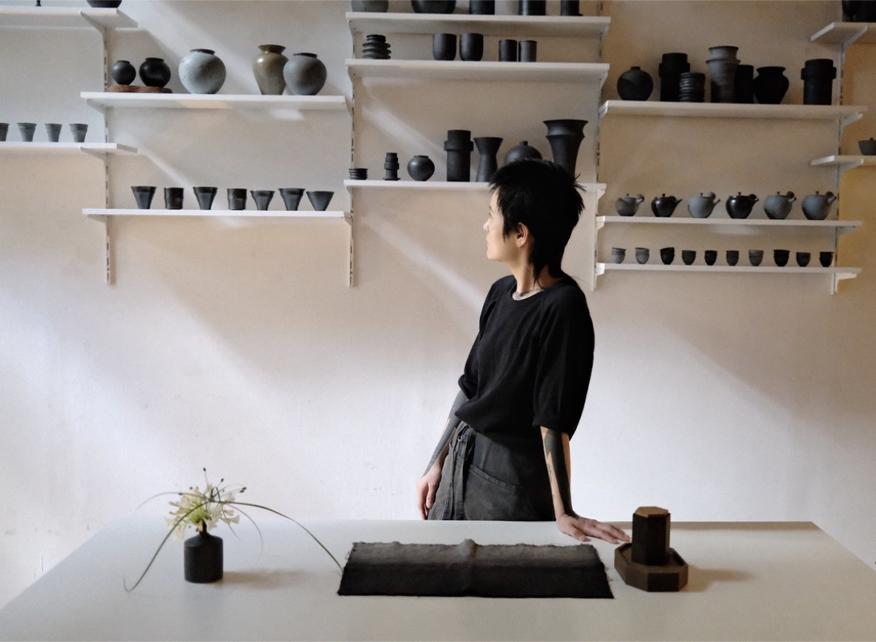 Saeam Kwon beside shelves of ceramics in her studio