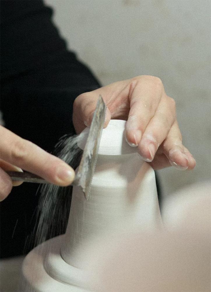 Hands refining the surface of a ceramic vessel