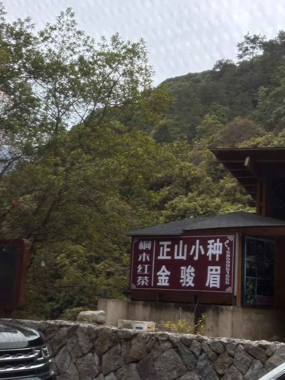 A tea shop sign beneath forested hills in Tongmu