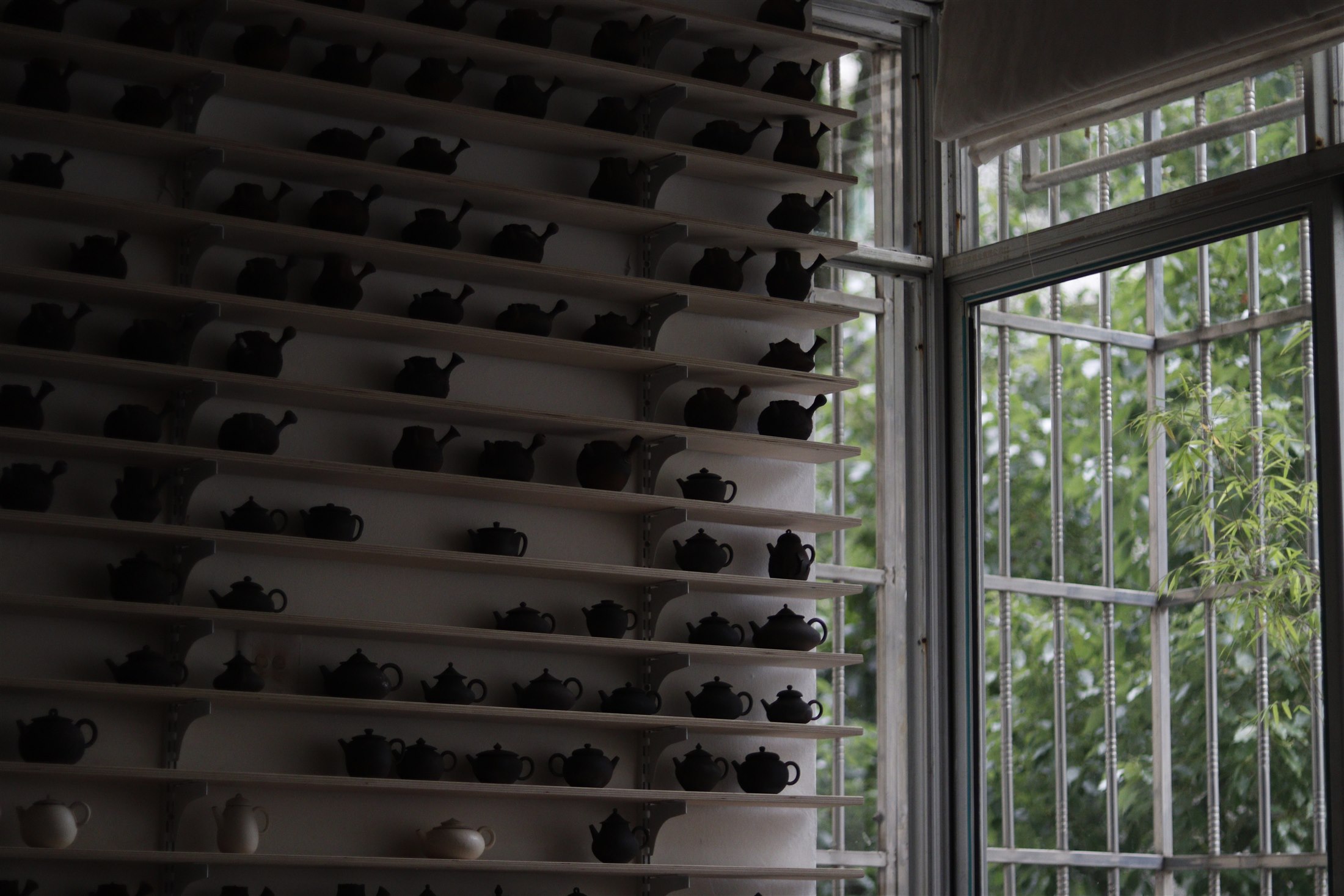 Shelves of teapots beside a studio window