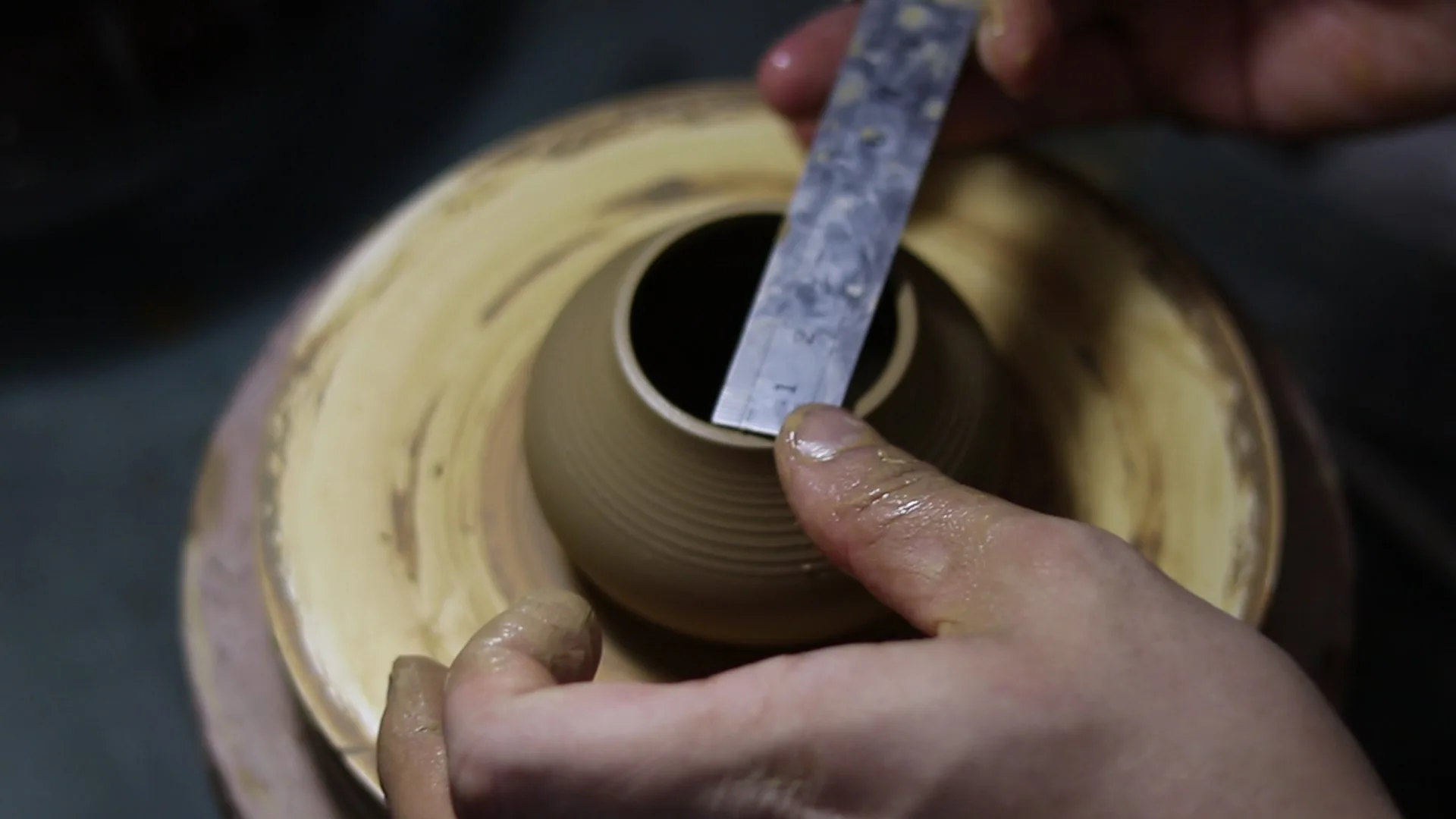 Measuring a clay vessel on the pottery wheel