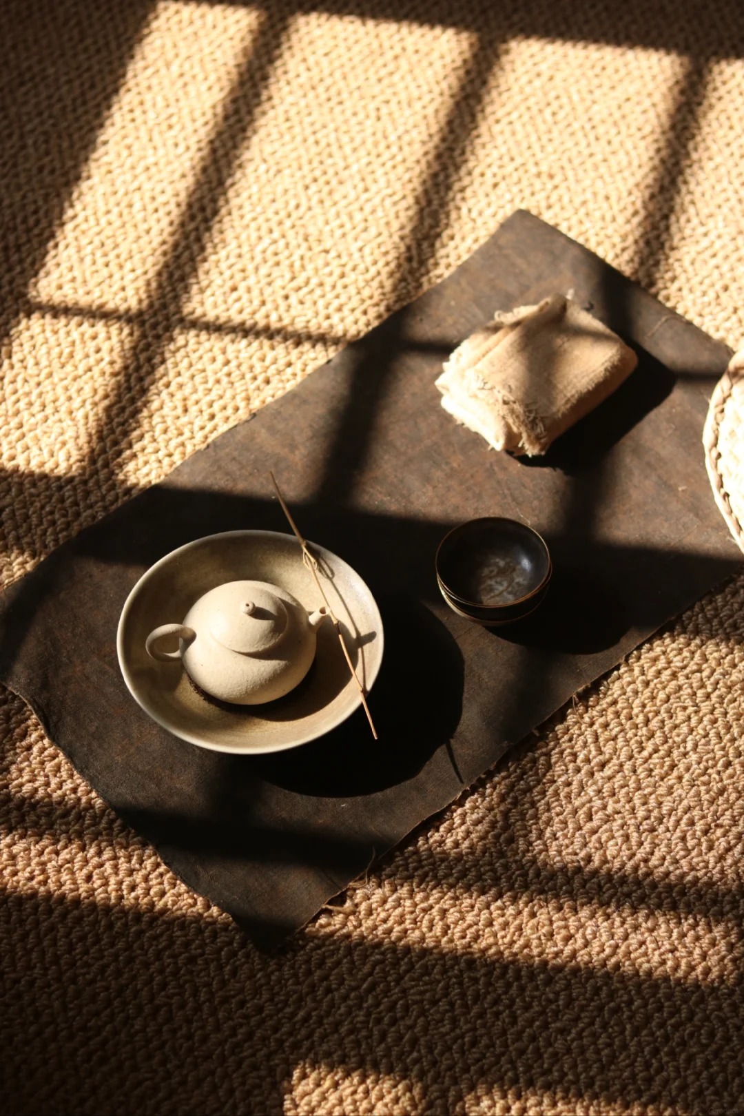 A teapot and cup arranged in warm window light